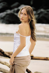 Woman wearing white silk camisole and taupe silk slip skirt