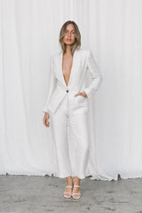 Model wearing white linen blazer and trousers posing in a studio