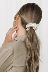 Close-up of model wearing a ponytail with a cream coloured silk scrunchie