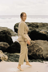 Model wearing a taupe linen blazer and trouser posing by the beach