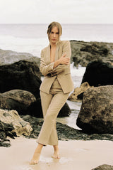 Model wearing a taupe-coloured suit posing on the beach