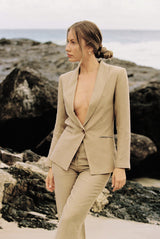 Model wearing a taupe blazer and trouser posing on the beach