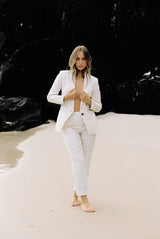 Model wearing a white linen suit by the beach