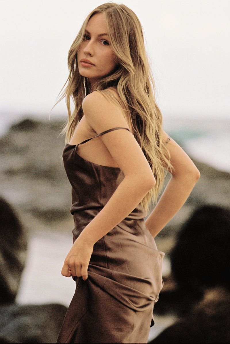Close-up of woman wearing a brown silk slip dress by the beach