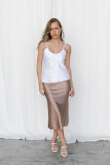Model wearing white silk camisole and taupe slip skirt posing in a studio