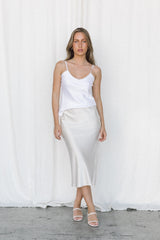 Model wearing white silk camisole and cream silk skirt posing in a studio