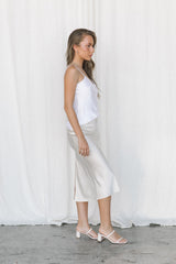 Model wearing white silk camisole and cream silk slip skirt posing in a studio