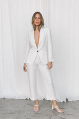 Model wearing white linen suit posing in a studio