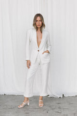 Model wearing a white linen suit posing in a studio