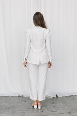 Back view of a model wearing a white linen suit posing in a studio