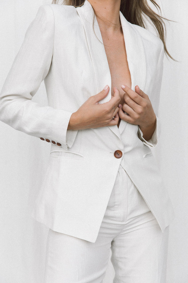 Close-up of model wearing a white linen suit posing in a studio