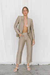 Model wearing a taupe linen blazer and trouser posing in a studio