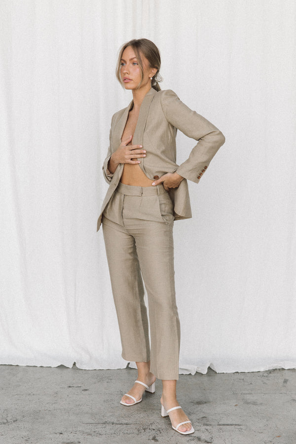 Model wearing a taupe linen blazer and trouser posing in a studio