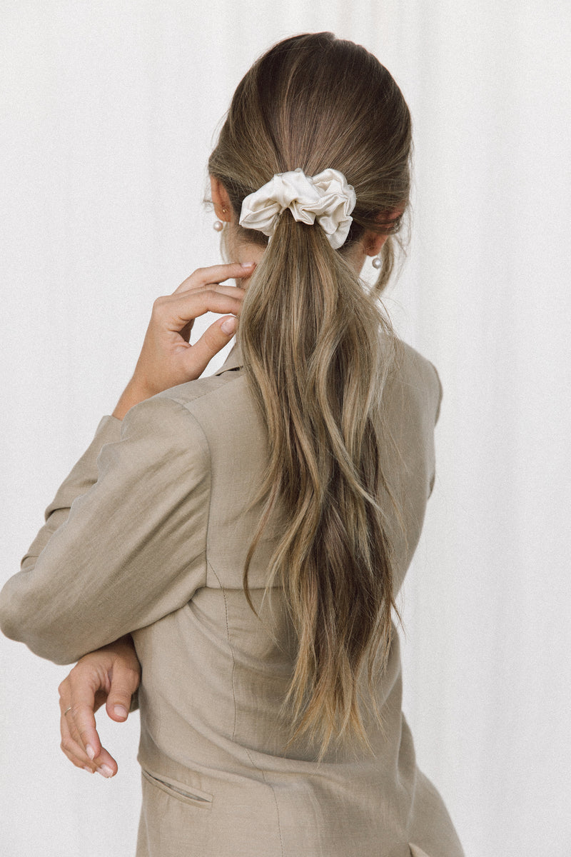 Back view of a model wearing a ponytail with a cream coloured silk scrunchie