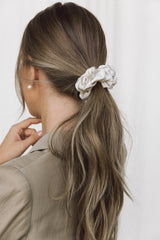 Close-up of a model wearing a ponytail with a cream coloured silk scrunchie